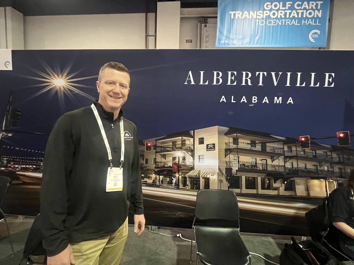 a man posing in front of a tradeshow booth at real estate conference